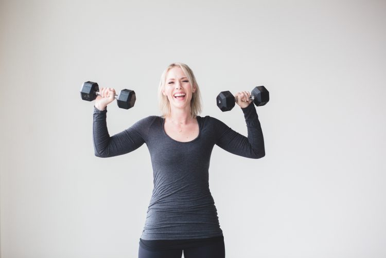 Happy woman lifting dumbbells - Three vital tips for the beginner's fitness journey blog